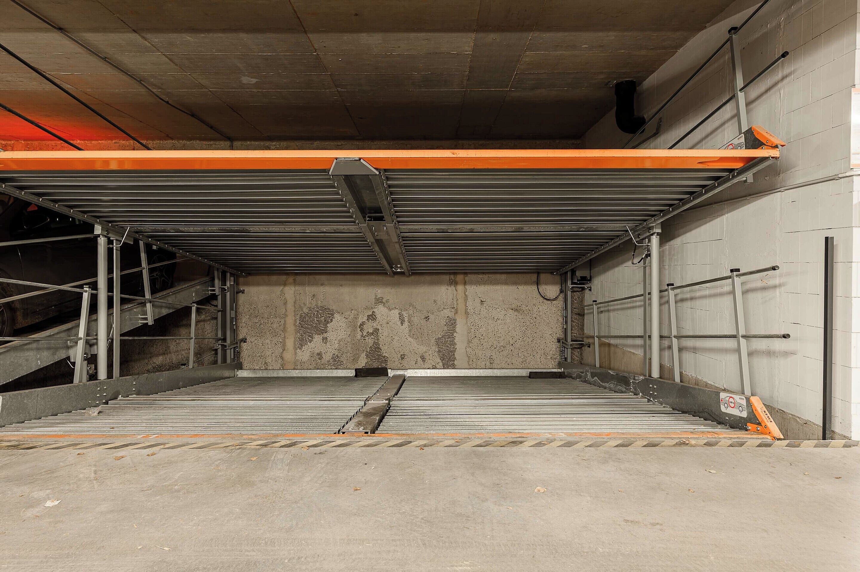 Un garaje de estacionamiento vacío con paredes de concreto, escaleras de metal y una puerta cerrada.
