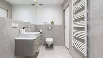 A modern bathroom with a built-in sink, toilet, and a towel rack.