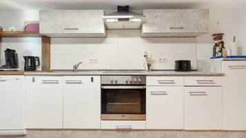 Eine moderne Küche mit weißen Schränken, einem eingebauten Backofen und einer Edelstahl-Dunstabzugshaube.