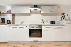 Een moderne keuken met witte kasten, een ingebouwde oven en een roestvrijstalen afzuigkap.