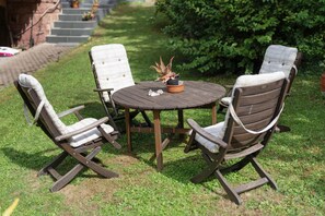A round wooden table with four chairs, each with a cushioned seat and backrest.