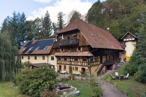 A traditional chalet with a sloped roof, wooden balconies, and a garden area with outdoor seating.