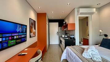 Une chambre d’hôtel équipée d’un lit, d’un bureau, d’une télévision et d’une kitchenette.