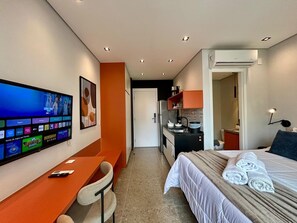 Une chambre d’hôtel équipée d’un lit, d’un bureau, d’une télévision et d’une kitchenette.