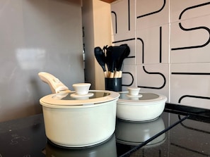 Deux pots en céramique blanche, dotés de couvercles, sont posés sur un comptoir noir.