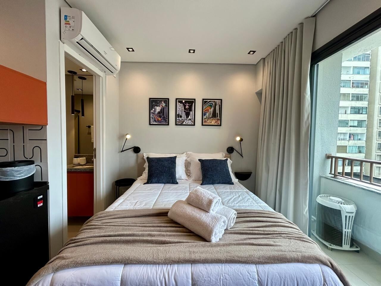 Een hotelkamer met een bed, kunst aan de muur en uitzicht op de stad.