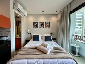 Une chambre d’hôtel avec un lit, des œuvres d’art au mur et une vue sur la ville.