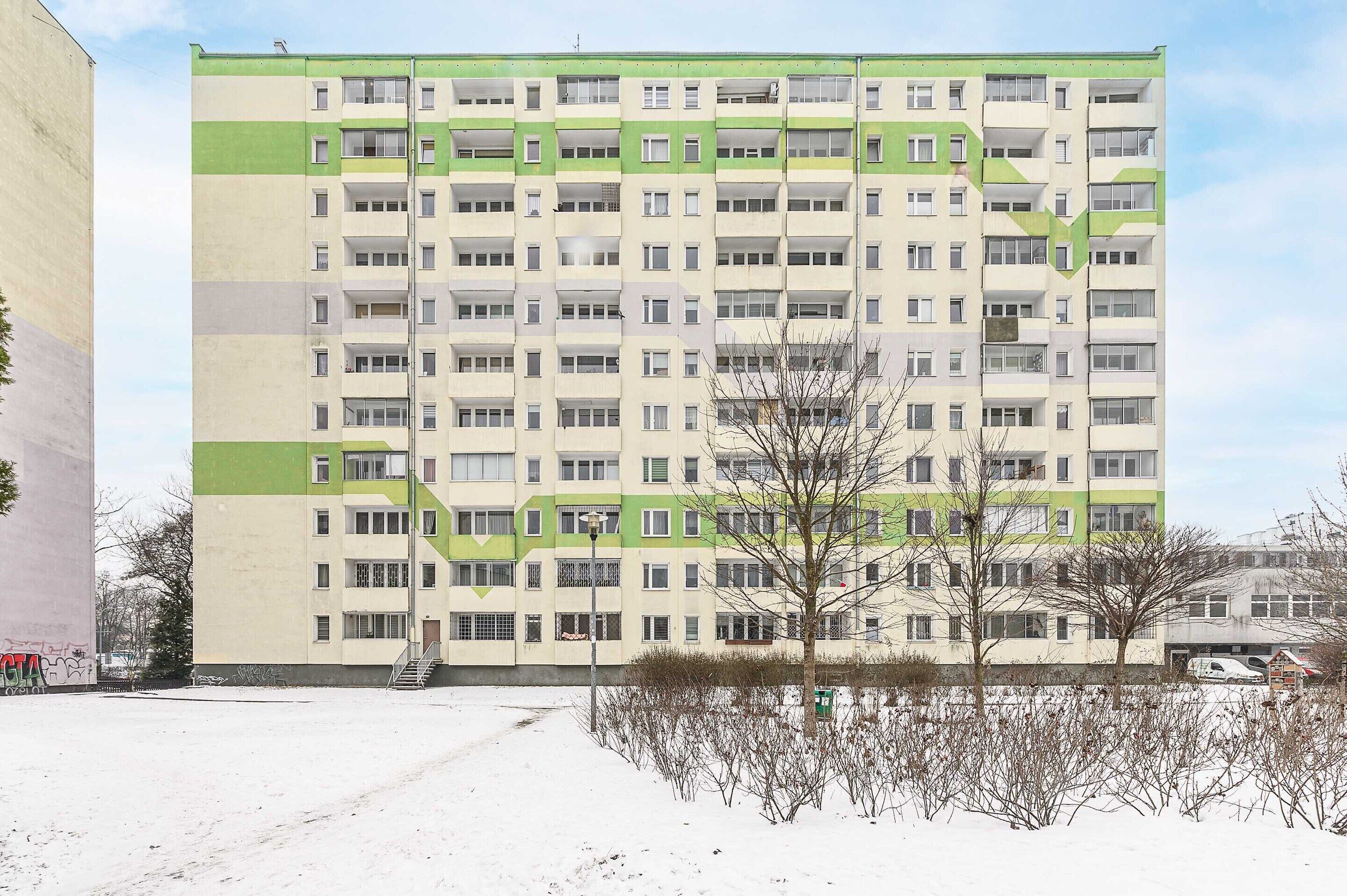 En flervåningsbyggnad med bostäder, en symmetrisk fasad, balkonger och en central trappa.