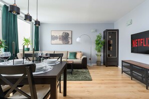 A modern living room with a dining area, a sofa, a painting, a TV, and a bookshelf. - Warsaw Flat Near Old Town (Warsaw)