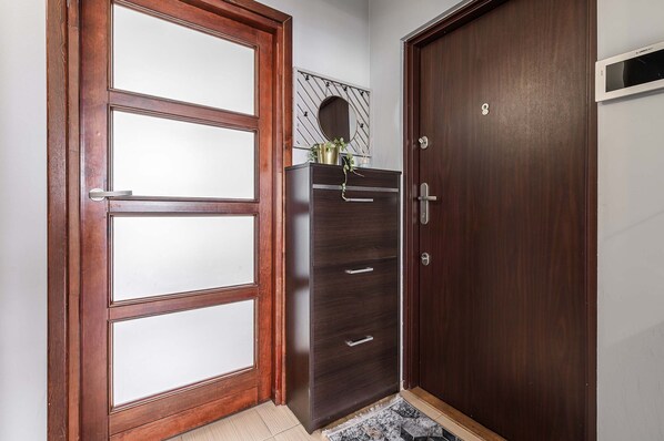A room with a wooden door, a dark wooden cabinet with drawers, and a small mirror on the wall. - Warsaw Flat Near Old Town (Warsaw)
