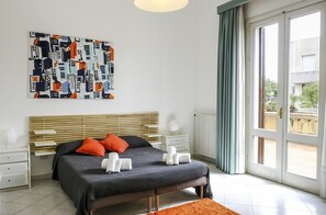 A bedroom with a bed, bedside tables, a radiator, and a window with curtains. - Villa in Sicily With Pool Near Erice & Trapani (Marsala)