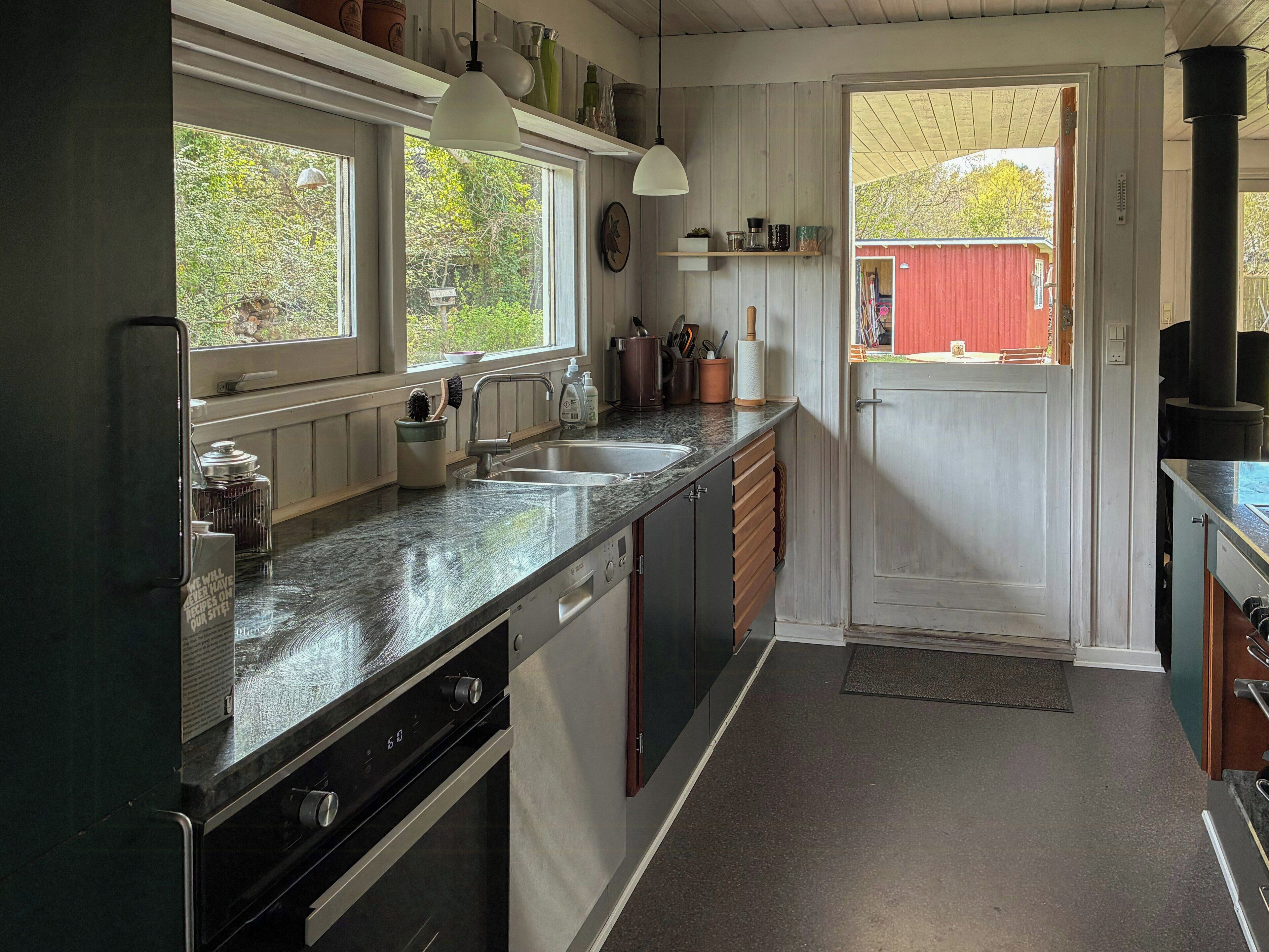 Eine Küche mit Backofen, Spüle und Fenster.