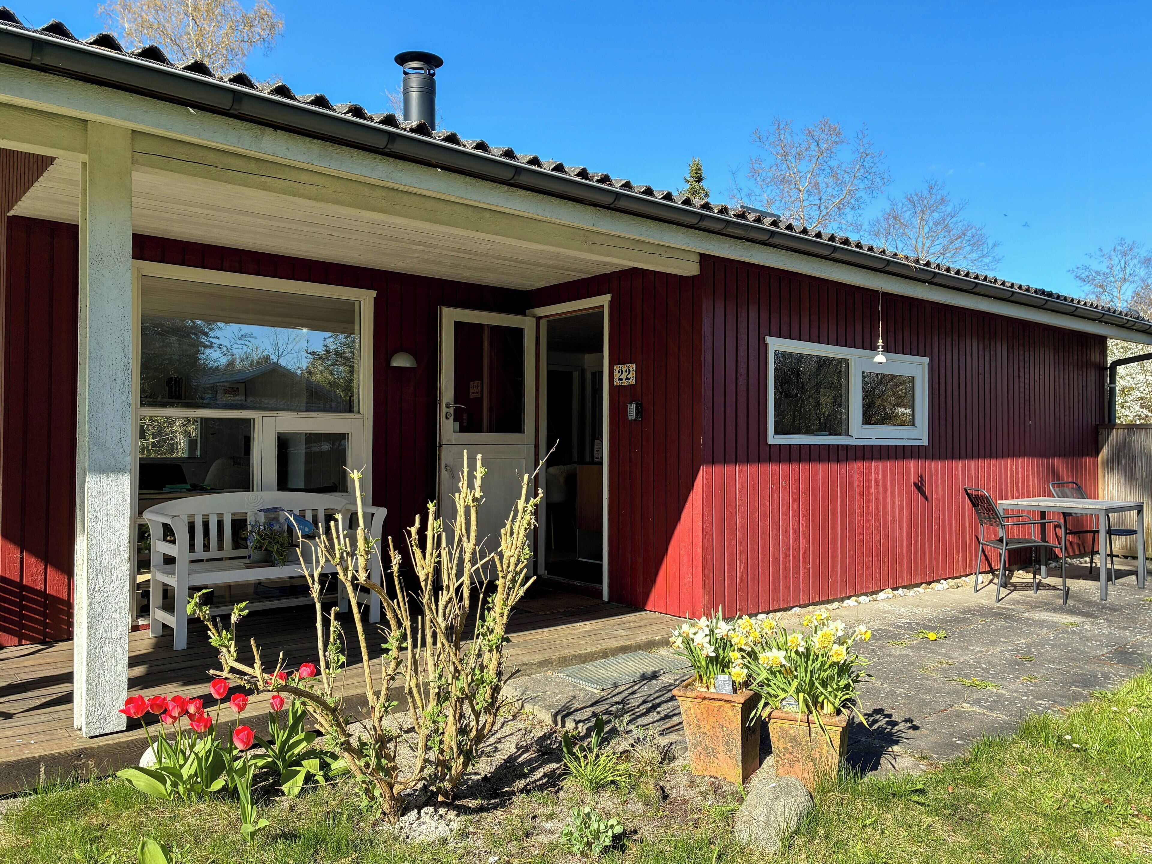 A red building with a covered porch, a white door, and a window.