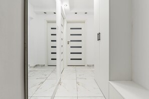 A corridor with white doors, a marble floor, and a modern light fixture on the ceiling. - Warsaw City Stay for Families (Warsaw)