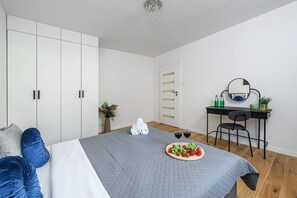 A bedroom with a bed, a desk with a chair, a wardrobe, and a mirror on the wall. - Warsaw City Stay for Families (Warsaw)