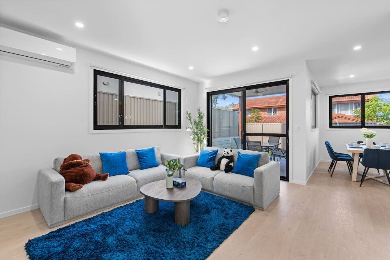A modern living room with a grey sofa, blue cushions, a round coffee table, and a blue rug.