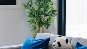 Ein graues Sofa mit zwei blauen Kissen und einem Panda-Plüschtier.