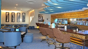 A bar area with a counter, seating, and a bar stocked with bottles.