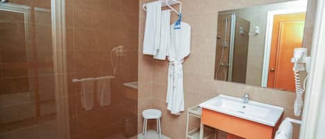 Baño con ducha, lavamanos, espejo y toallero.
