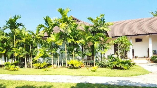 A building with a tiled roof and a well-maintained lawn with palm trees.