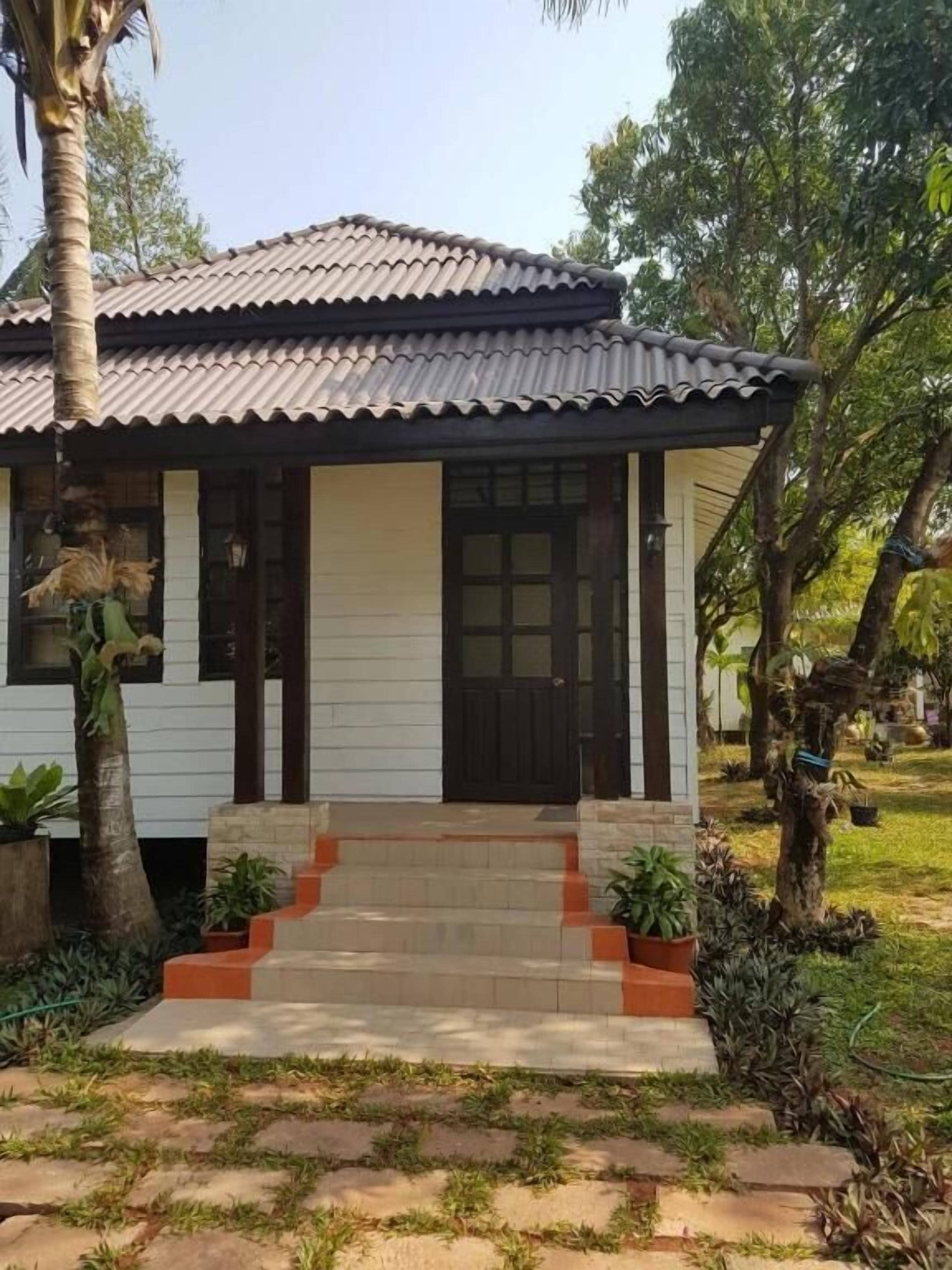 A single-story house with a tiled roof, a front door, and a small porch with steps leading to the entrance.
