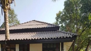 A single-story house with a tiled roof, a front door, and a small porch with steps leading to the entrance.