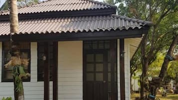A single-story house with a tiled roof, a front door, and a small porch with steps leading to the entrance.
