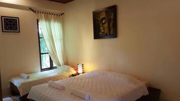 A hotel room with two beds, a window with curtains, a wall-mounted painting, and a bedside lamp.