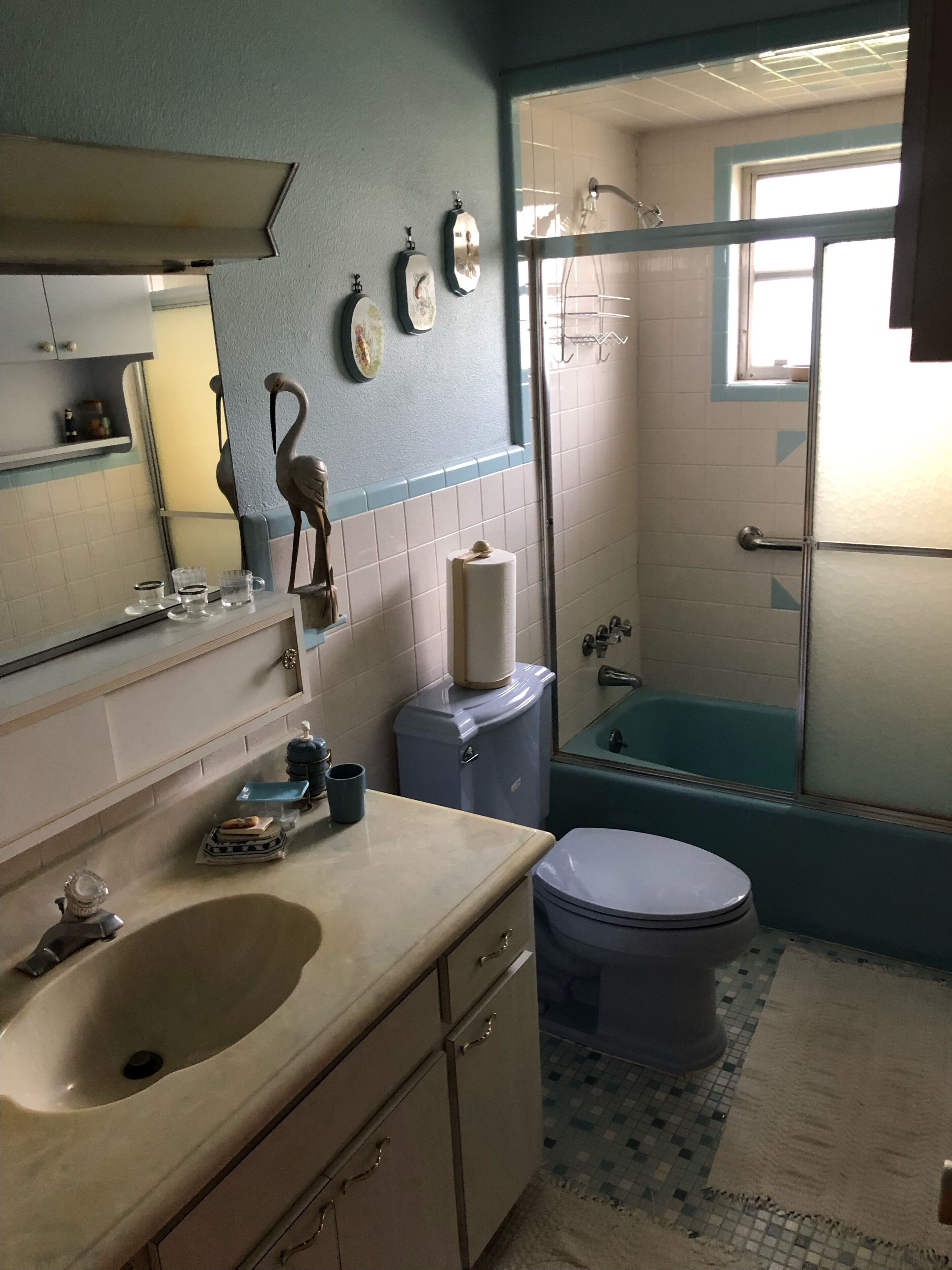Un baño con lavabo, inodoro y bañera. Hay un espejo sobre el lavabo, y se ve un perchero para toallas.