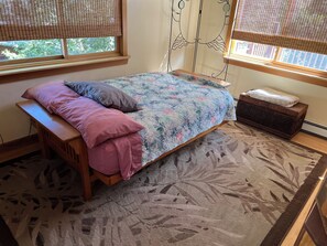 Un dormitorio con cama, un banco, una mesita y una ventana con persianas.
