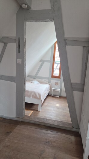 Un dormitorio con techo inclinado, una cama, una mesita de noche y una ventana.