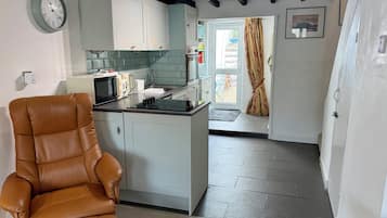 A modern kitchen with a built-in island, a brown leather chair, and a dining area with a patterned curtain.