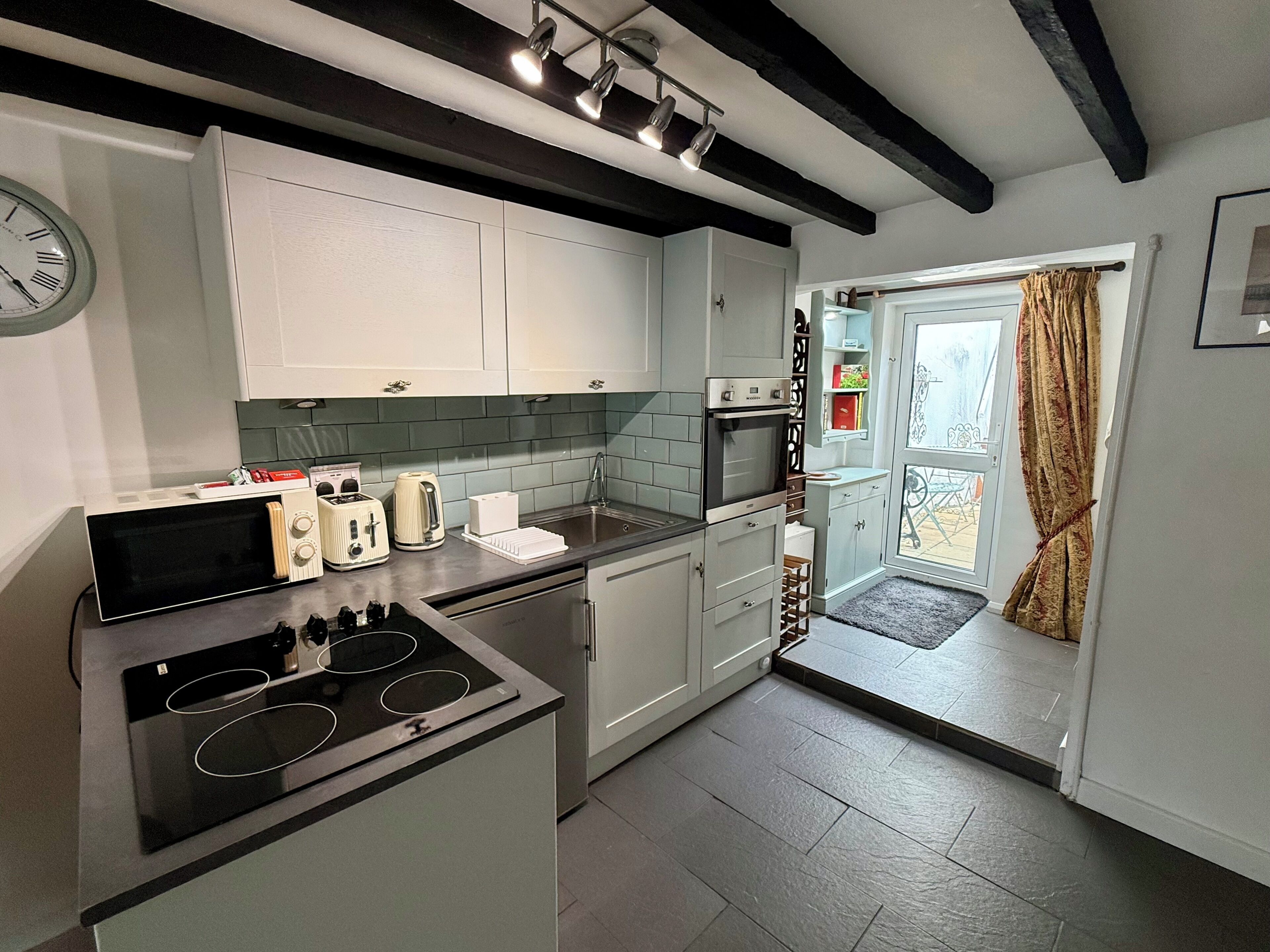 Een moderne keuken met een ingebouwde kookplaat, een spoelbak en een raam met gordijnen.