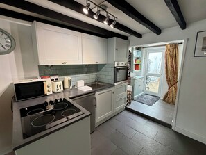 A modern kitchen with a built-in stove, a sink, and a window with curtains.