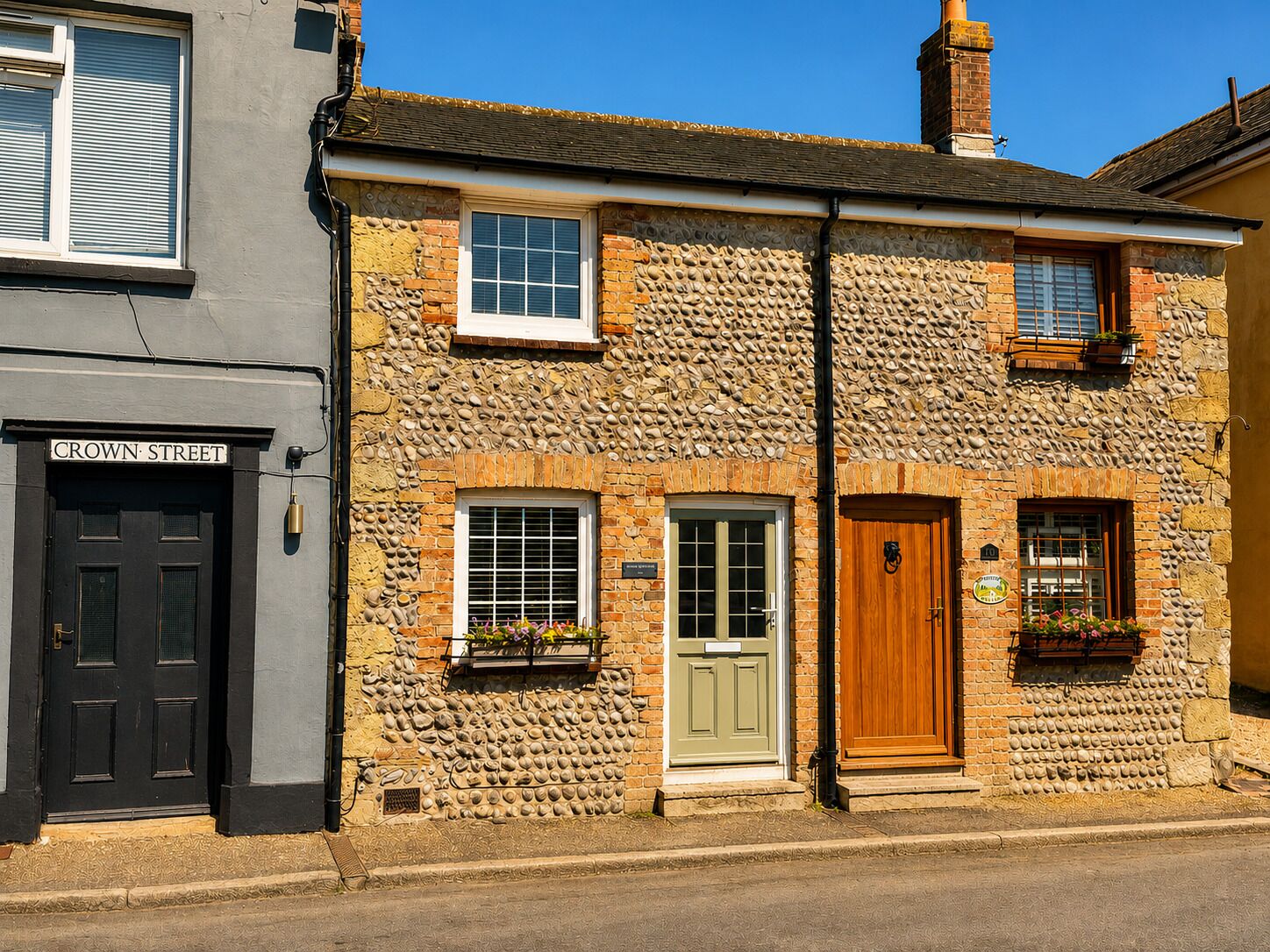 A building with a stone facade, a black door, and a sign reading 'CROWN STREET'.