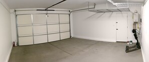 Eine Garage mit einer weißen Tür, einem Deckenventilator und einem an der Wand montierten Warmwasserbereiter.