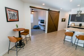 A modern kitchen with a bar area, wooden flooring, and a sliding barn door. - Star Light, Estrella Mountain Ranch (Goodyear)