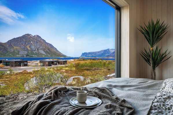 A bedroom with a view of a mountain and a body of water.