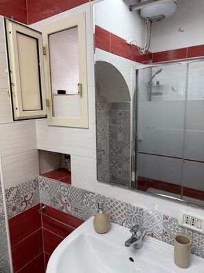 Ein Badezimmer mit Dusche, Waschbecken und Spiegel.