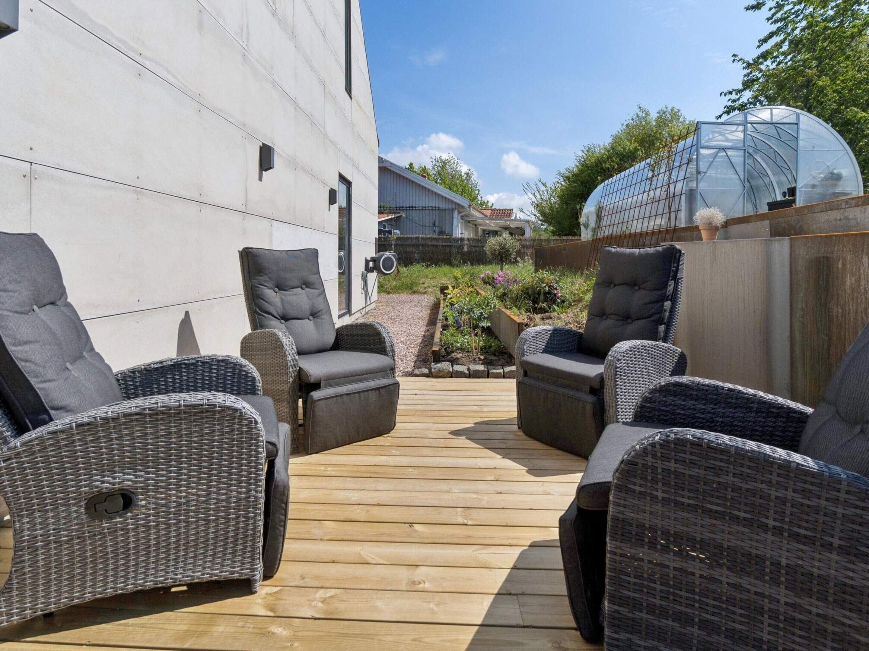 Un espace extérieur aménagé avec des chaises en osier et une terrasse en bois.