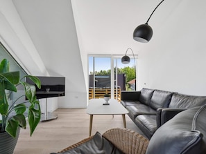 A modern living room with a leather sofa, a white coffee table, and a television on a stand. - 4 Star Holiday Home in Allinge (Allinge)
