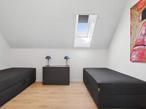 Ein Zimmer mit zwei dunkelgrauen Sofas, einem kleinen, dunkelgrauen Schrank und einem Oberlicht.