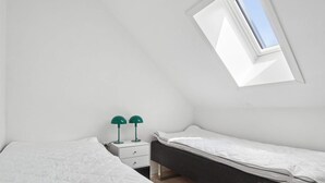 A room with two beds, a small white nightstand, and a skylight. - 4 Star Holiday Home in Allinge (Allinge)