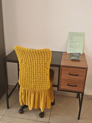 A chair with a yellow textured cover, a desk with a drawer, and a document on the desk. - Un T2 récent  , confortable  dans un petit  immeuble au coeur de Saint Denis (Saint-Denis)