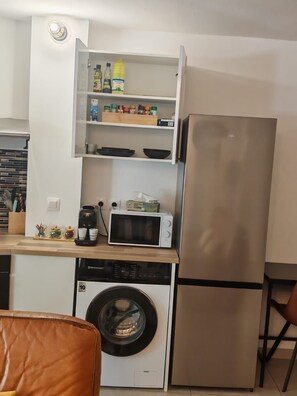 A compact kitchen with a built-in washing machine, a microwave, and a refrigerator. - Un T2 récent  , confortable  dans un petit  immeuble au coeur de Saint Denis (Saint-Denis)