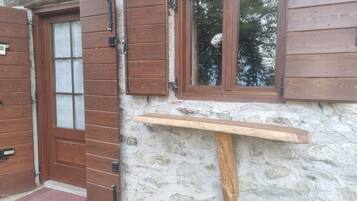 Eine rustikale Holztür mit einem Glasfenster, eine Steinwand und ein Holzregal.