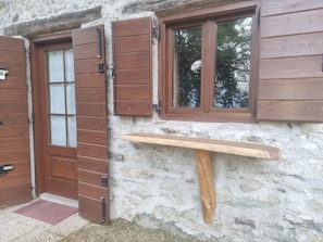 Une porte en bois rustique avec un panneau de verre, un mur en pierre et une étagère en bois.