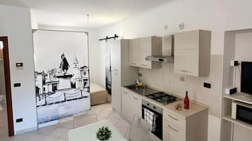Una cucina moderna con zona pranzo, un fornello, pensili e una piccola TV.