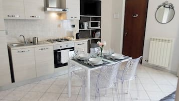 Una cucina moderna con piano cottura a gas, lavello e forno a microonde. È presente un tavolo da pranzo con sedie e un vaso di fiori.