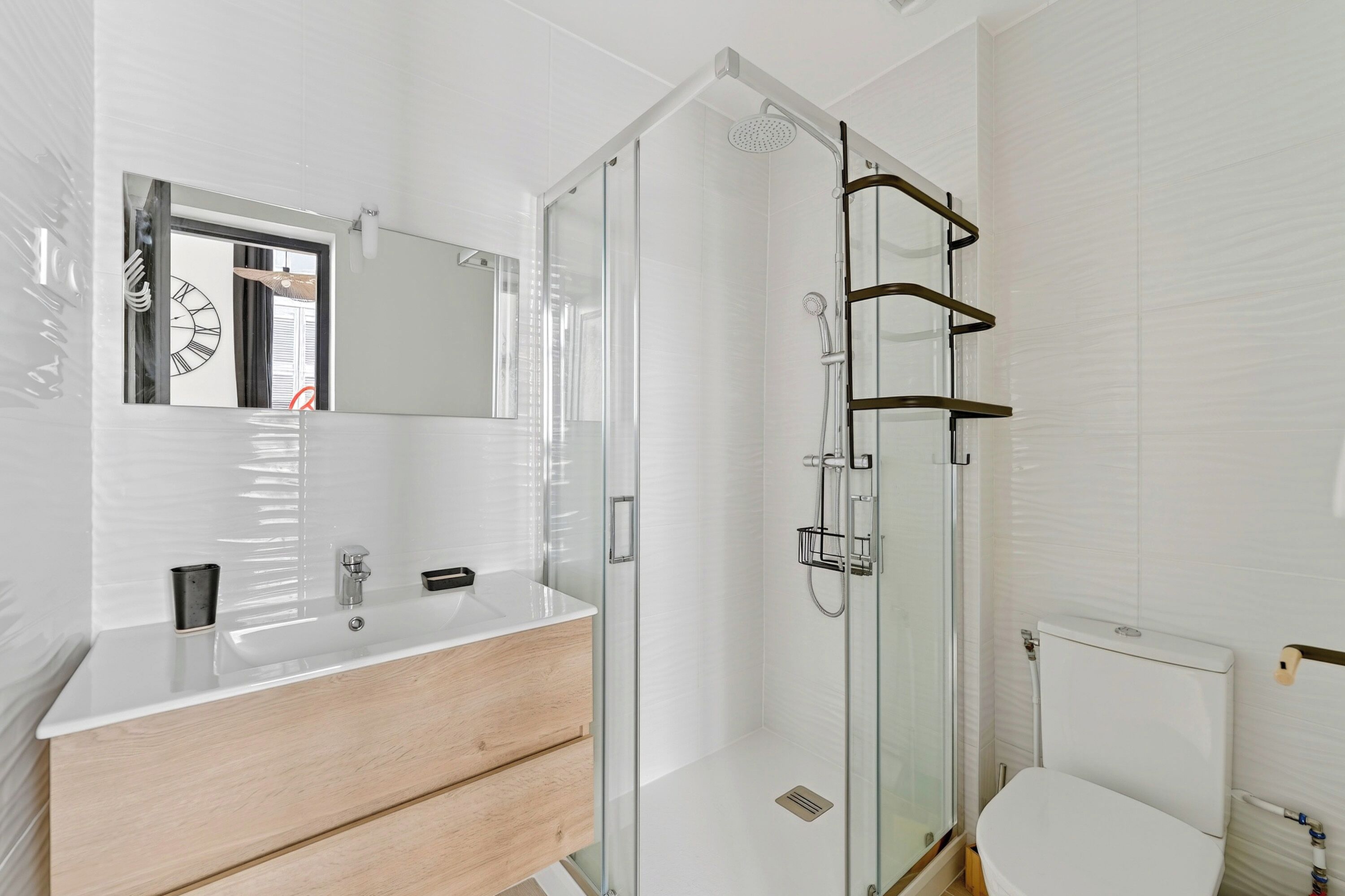 Une salle de bain moderne avec une douche à parois de verre, un meuble-lavabo en bois et un grand miroir.